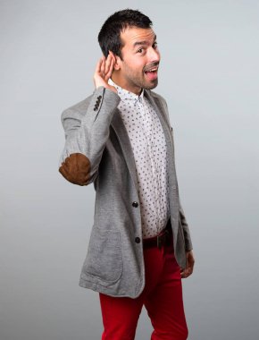 Yakışıklı adam gri arka plan üzerine bir şey dinleme