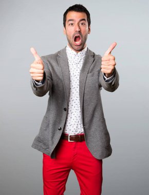 Gri arka plan üzerinde başparmak ile yakışıklı adam