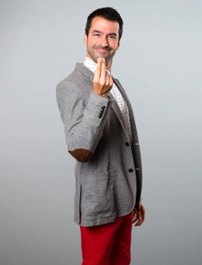 Yakışıklı adam yapma para jest gri arka plan üzerinde