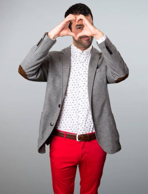 Yakışıklı adam gri arka plan üzerinde elleriyle bir kalp yapma