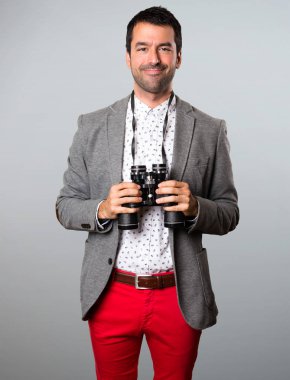 Gri arka plan üzerinde dürbün ile mutlu yakışıklı adam