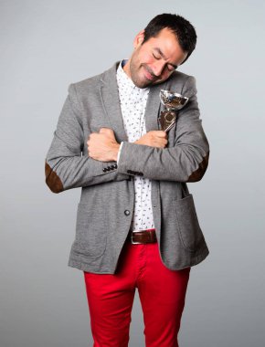 Bir kupa gri arka plan üzerinde tutan mutlu yakışıklı adam