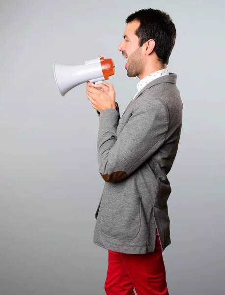 Knappe man met een megafoon op grijze achtergrond — Stockfoto