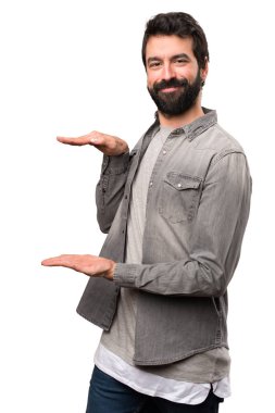 Bir şey beyaz arka plan üzerinde tutan sakallı yakışıklı adam