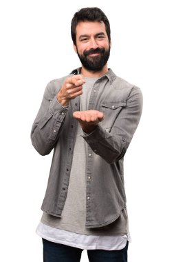 Bir şey beyaz arka plan üzerinde tutan sakallı yakışıklı adam