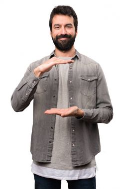 Bir şey beyaz arka plan üzerinde tutan sakallı yakışıklı adam