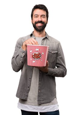 Popcorns beyaz arka plan üzerinde yemek sakallı yakışıklı adam