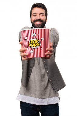 Popcorns beyaz arka plan üzerinde yemek sakallı yakışıklı adam