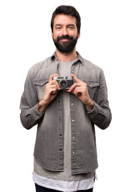 Beyaz arka plan üzerinde bir kamera tutarak sakallı yakışıklı adam