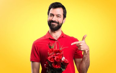 Yakışıklı adam sarı arka plan üzerinde sunulması çiçek tutan