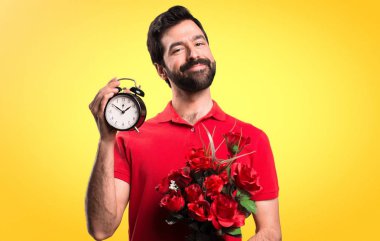 Yakışıklı adam Vintage saati sarı arka plan üzerinde tutarak çiçek tutan