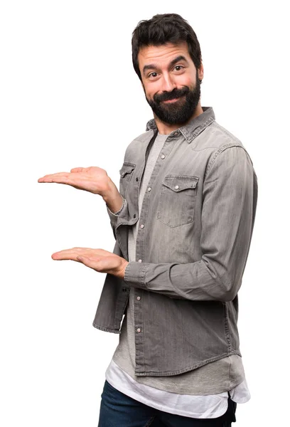 Bonito homem com barba apresentando algo no fundo branco — Fotografia de Stock
