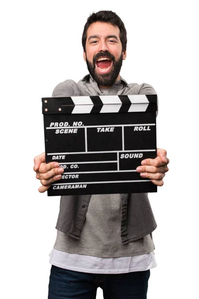 Hombre guapo con barba sosteniendo una tabla de aplausos en el fondo blanco —  Fotos de Stock