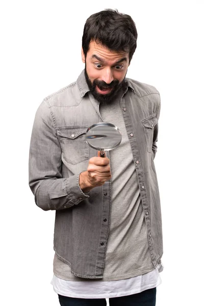 Surprised Handsome man with beard with magnifying glass on white — Stock Photo, Image