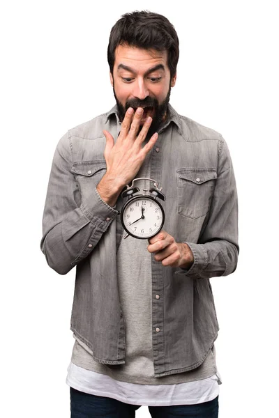 Überrascht schöner Mann mit Bart hält Vintage-Uhr auf weiß — Stockfoto