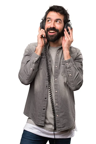 Knappe man met baard luisteren muziek op witte achtergrond — Stockfoto