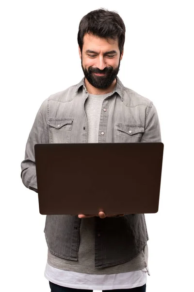Schöner Mann mit Bart und Laptop auf weißem Hintergrund — Stockfoto