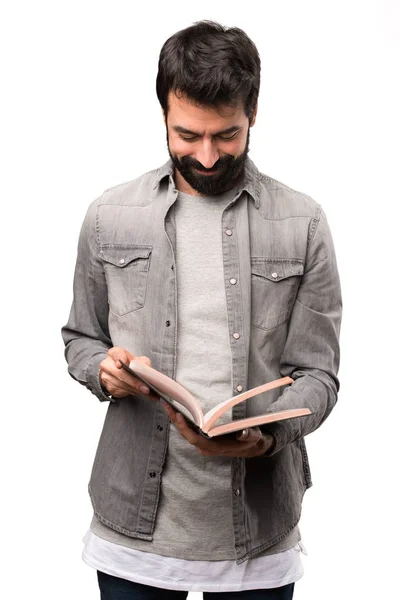 Hombre guapo con barba leyendo un libro sobre fondo blanco —  Fotos de Stock