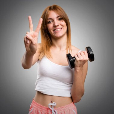 Güzel spor kadın iki gri backgr sayma dumbbells ile