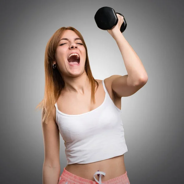 Bella donna sportiva con i manubri gridare su sfondo grigio — Foto Stock