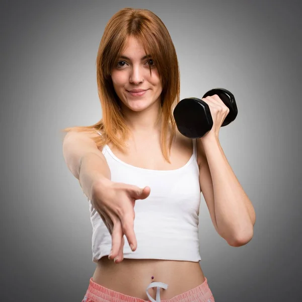 Beautiful sport woman with dumbbells making a deal on grey backg — Stock Photo, Image