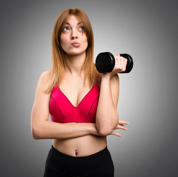 Mulher esporte bonita com halteres pensando em fundo cinza — Fotografia de Stock