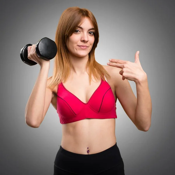 Beautiful sport woman with dumbbells proud of herself on grey ba — Stock Photo, Image