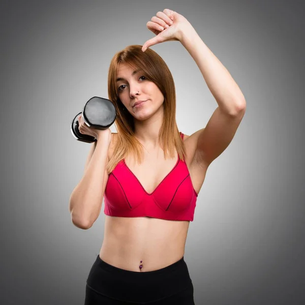 Hermosa mujer deportiva con mancuernas haciendo mala señal en gris b —  Fotos de Stock