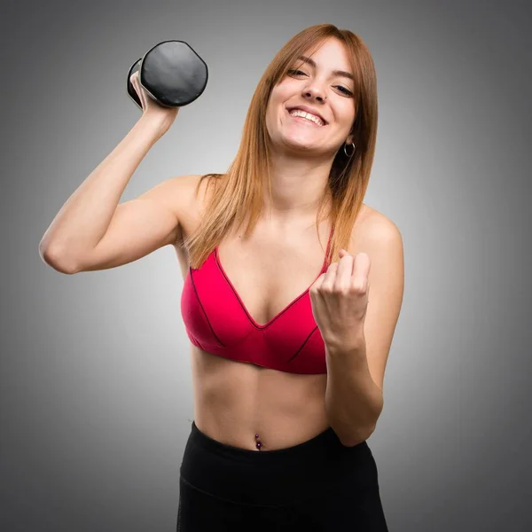 Счастливая красивая спортивная женщина с гантелями на сером фоне — стоковое фото