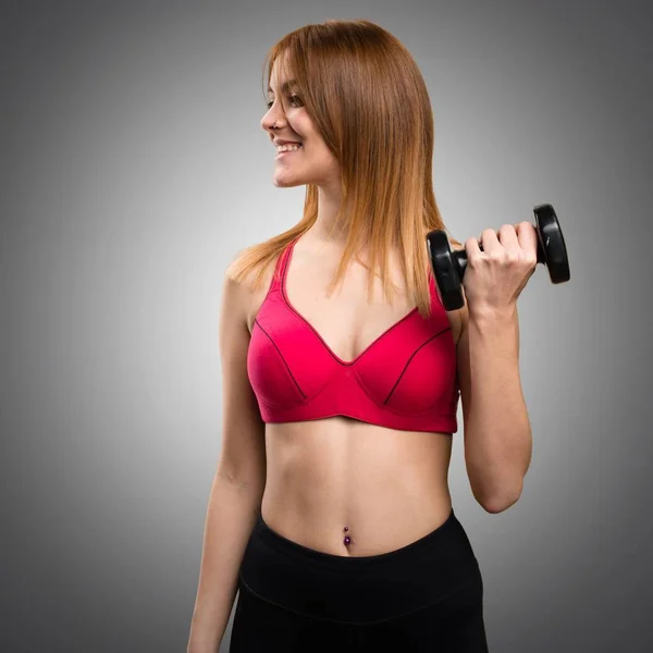 Beautiful sport woman with dumbbells looking lateral on grey bac — Stock Photo, Image