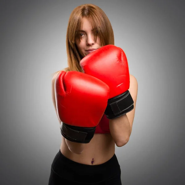 灰色の背景にボクシング グローブを持つ若いスポーツ女性 — ストック写真