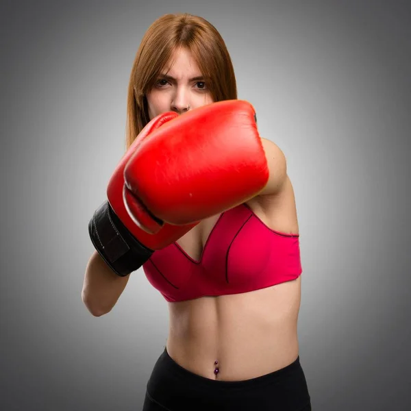 Jonge sport vrouw met bokshandschoenen op grijze achtergrond — Stockfoto