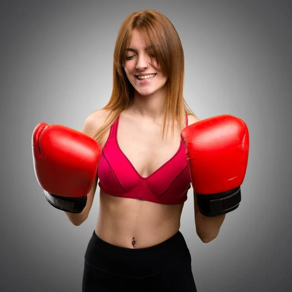 Jovem mulher esporte com luvas de boxe no fundo cinza — Fotografia de Stock