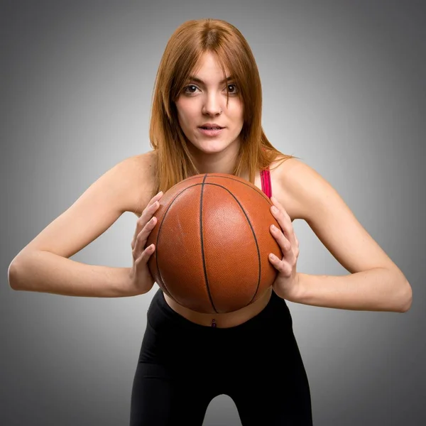 Pemuda olahraga wanita dengan bola basket pada latar belakang abu-abu — Stok Foto
