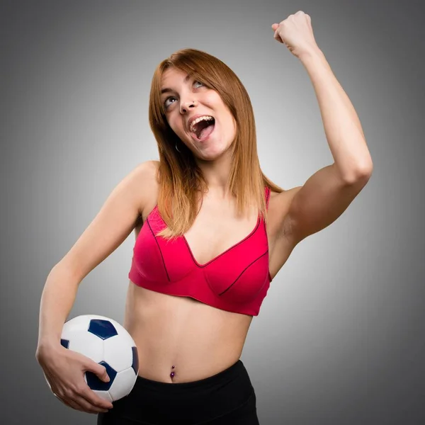 Joven deportista sosteniendo una pelota de fútbol sobre fondo gris — Foto de Stock