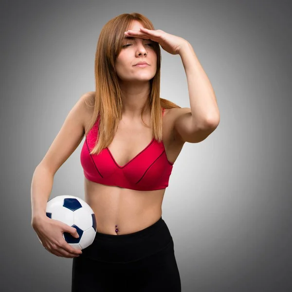 Молодая спортсменка держит футбольный мяч на сером фоне — стоковое фото