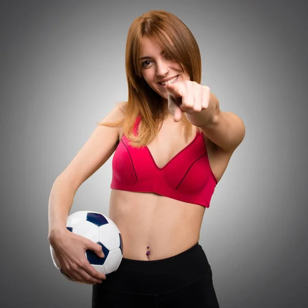 年轻体育妇女拿着一个足球在灰色背景 — 图库照片
