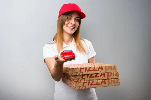 Pizza delivery woman holding little car on textured background