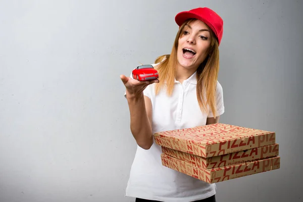 Pizza donna consegna tenendo piccola auto su sfondo strutturato — Foto Stock