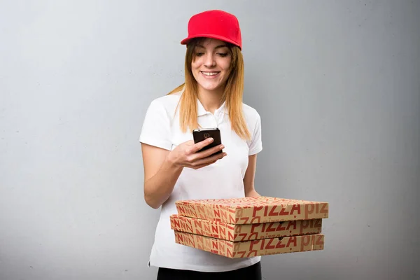 Доставка пиццы женщина разговаривает с мобильным на текстурированном фоне — стоковое фото