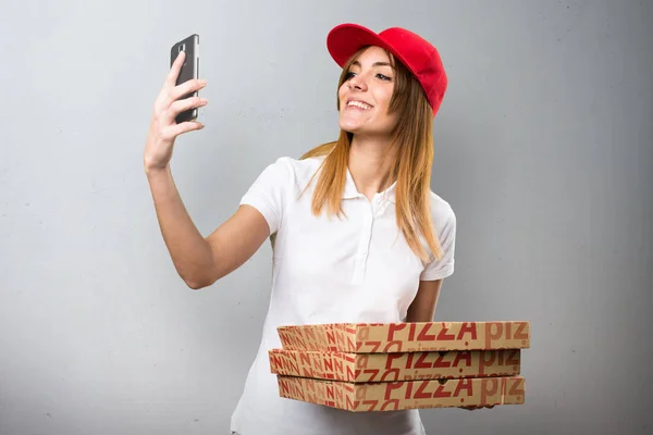 Pizza delivery woman making a selfie on textured background