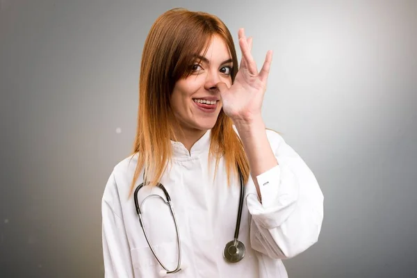 Молодая женщина-врач шутит на сером фоне — стоковое фото