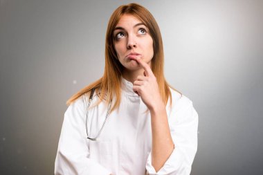 Gri arka plan üzerine şüpheleri genç doktor kadın
