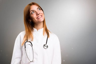 Gri arka plan üzerinde arayan genç doktor kadın