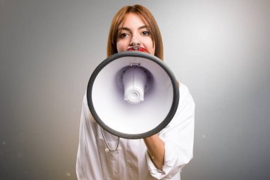 Bir megafon gri arka plan üzerinde tutan genç doktor kadın