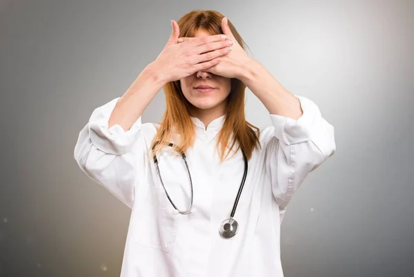 Jovem médica mulher cobrindo seus olhos em fundo cinza — Fotografia de Stock