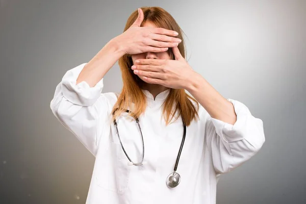 Junge Ärztin bedeckt ihr Gesicht auf grauem Hintergrund — Stockfoto
