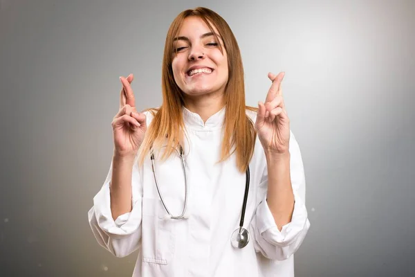 Junge Ärztin mit Daumendrücken auf grauem Hintergrund — Stockfoto