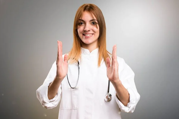 Молодая доктор женщина держит что-то на сером фоне — стоковое фото