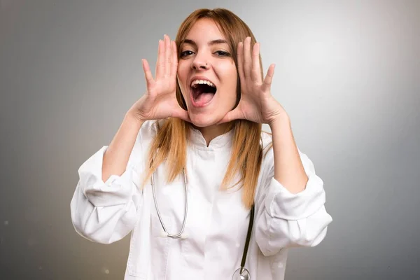 Jeune médecin femme faisant un geste de surprise sur fond gris — Photo